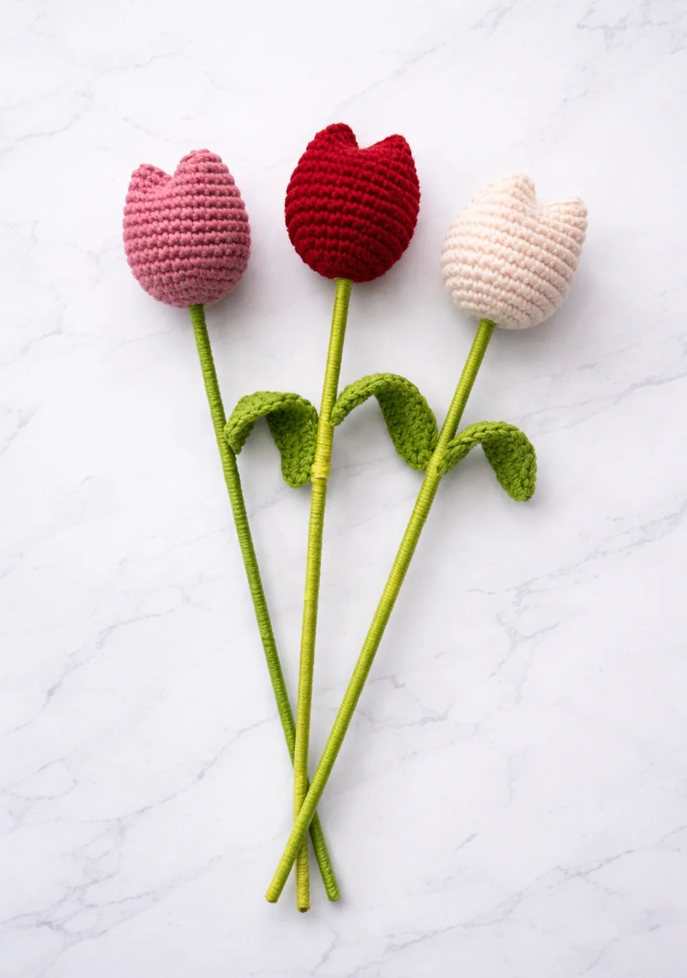 Tres tulipanes tejidos en tonos rosa, rojo y crema